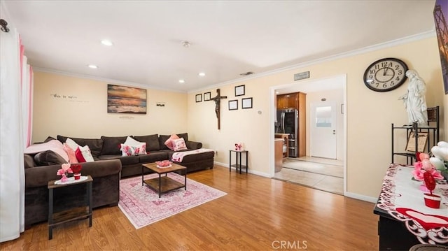 living room featuring ornamental molding, baseboards, and wood finished floors