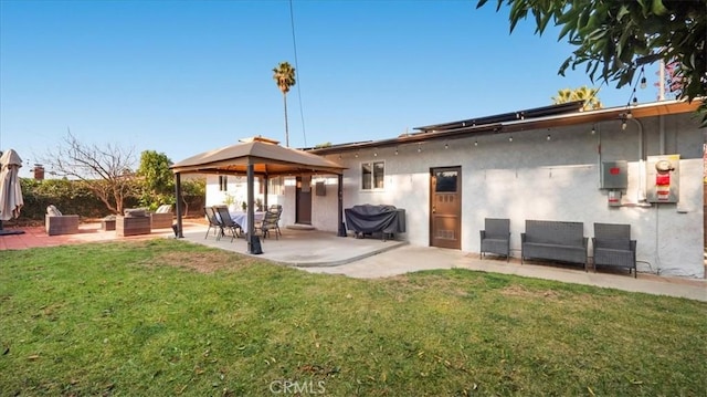 rear view of house with a patio area, a yard, a gazebo, and stucco siding