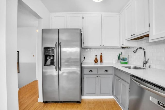 kitchen with white cabinetry, appliances with stainless steel finishes, sink, and light hardwood / wood-style flooring