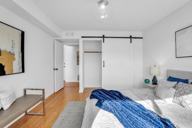 bedroom with a closet, hardwood / wood-style flooring, and a barn door