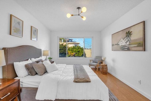 bedroom with hardwood / wood-style flooring, a chandelier, and a textured ceiling