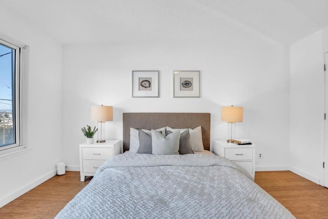 bedroom with vaulted ceiling and light hardwood / wood-style floors