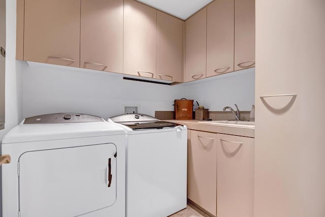 clothes washing area featuring separate washer and dryer, sink, and cabinets