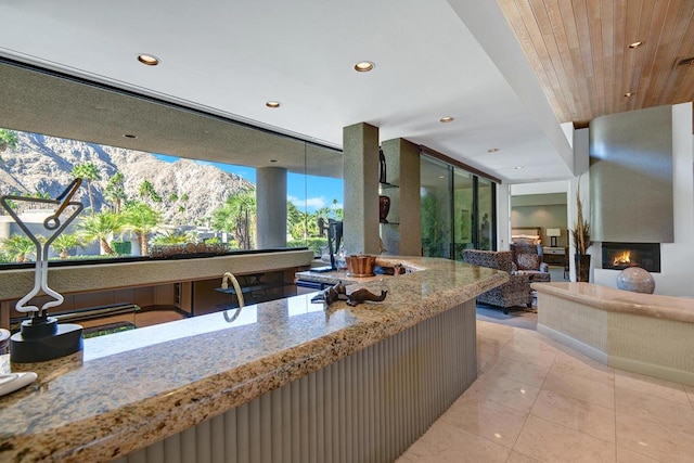 kitchen featuring a mountain view, a fireplace, wooden ceiling, and expansive windows