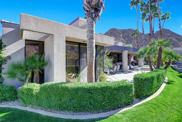 rear view of property with a mountain view, a lawn, and a patio