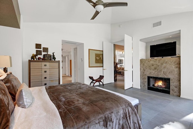 bedroom featuring ceiling fan, lofted ceiling, and a high end fireplace