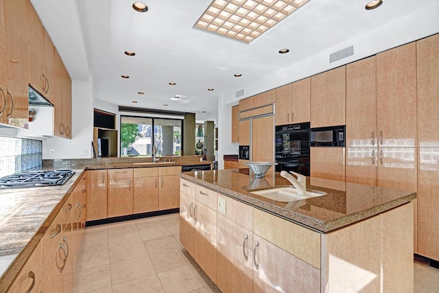 kitchen featuring sink, stone countertops, a center island, light brown cabinets, and black appliances