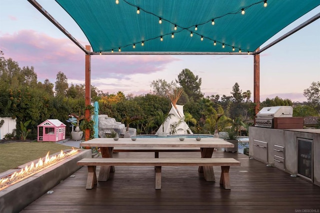 deck at dusk with a grill, area for grilling, and a fire pit