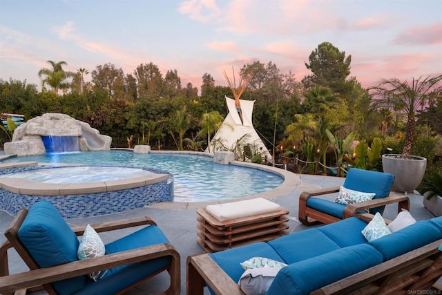 pool at dusk with pool water feature and an in ground hot tub