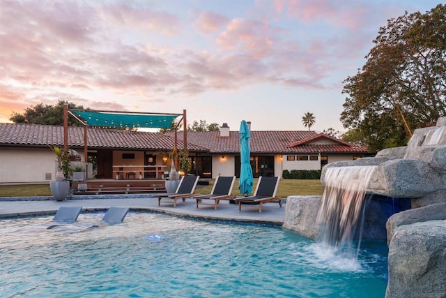 pool at dusk featuring a patio area and pool water feature