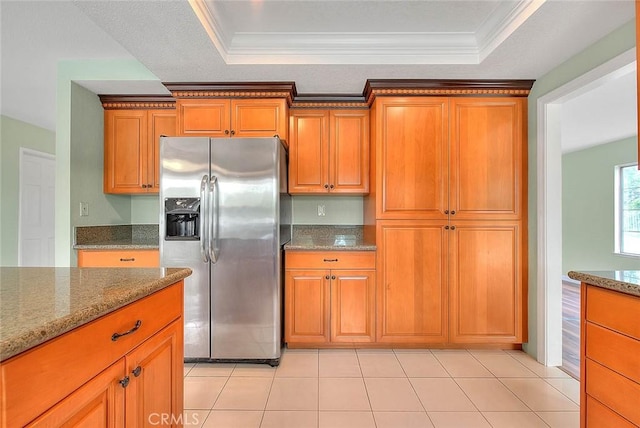 kitchen with light stone counters, stainless steel fridge with ice dispenser, light tile patterned floors, and a raised ceiling