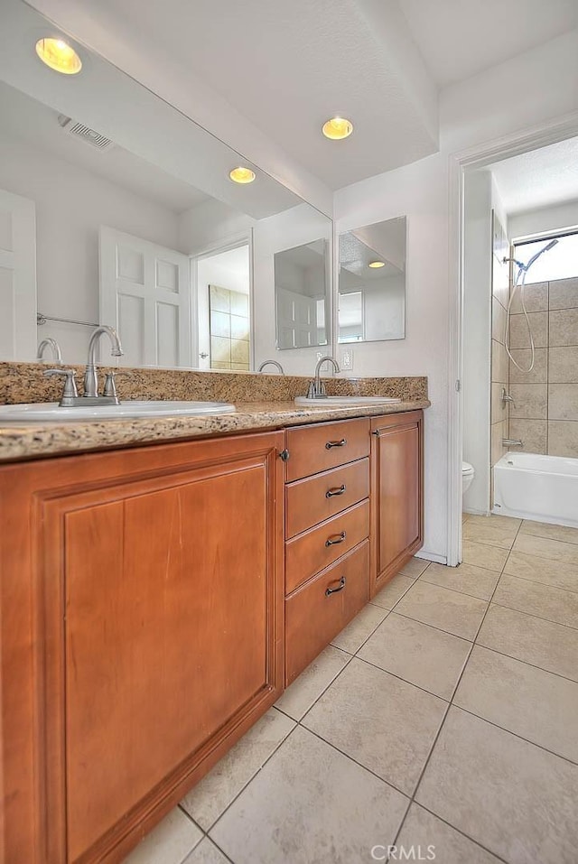 full bathroom featuring tile patterned flooring, vanity, tiled shower / bath combo, and toilet