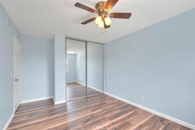 unfurnished bedroom with ceiling fan, dark hardwood / wood-style flooring, and a closet