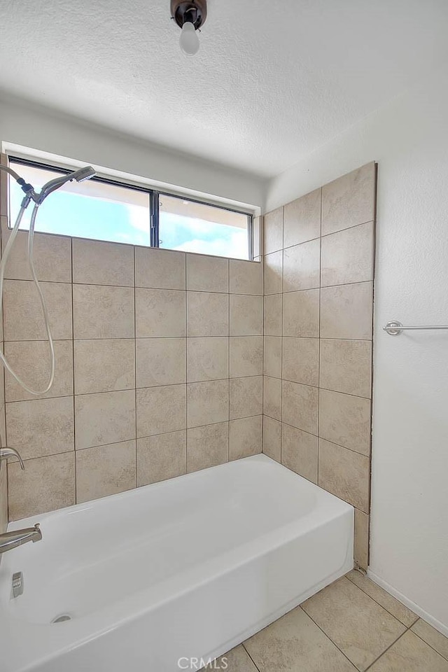 bathroom with tile patterned flooring, tiled shower / bath combo, and a textured ceiling