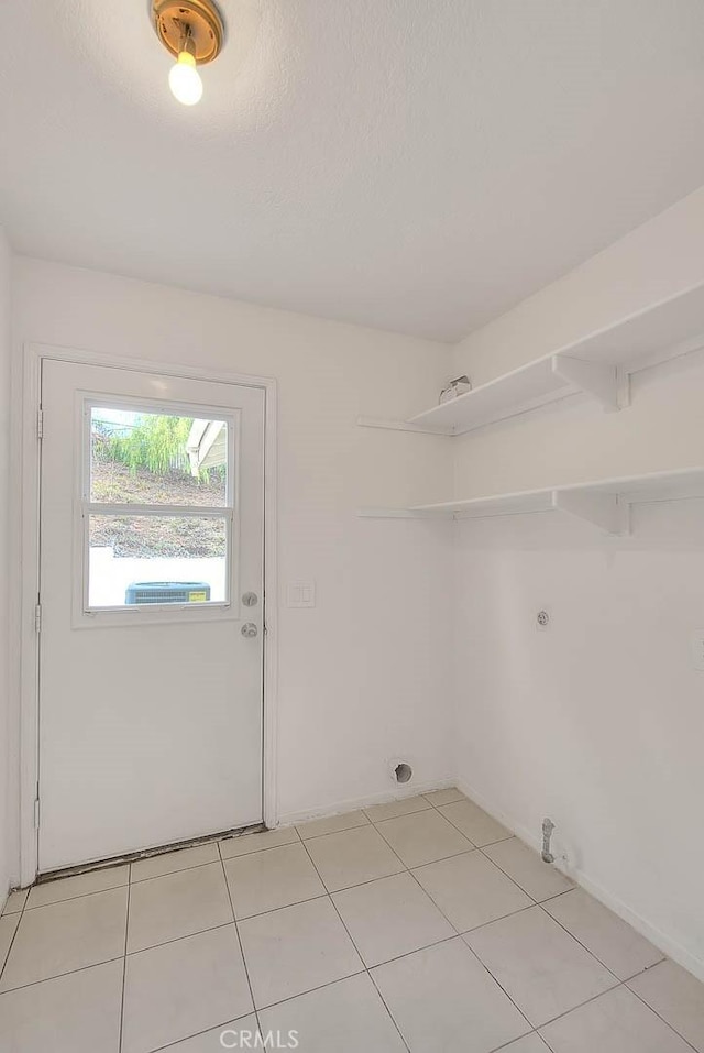 clothes washing area with light tile patterned flooring and a textured ceiling