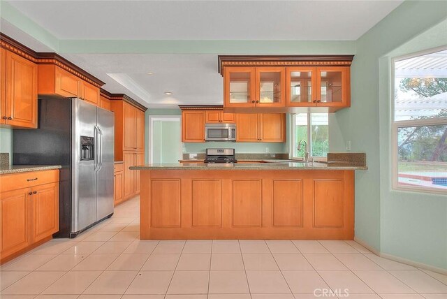 kitchen with sink, light tile patterned floors, kitchen peninsula, and appliances with stainless steel finishes