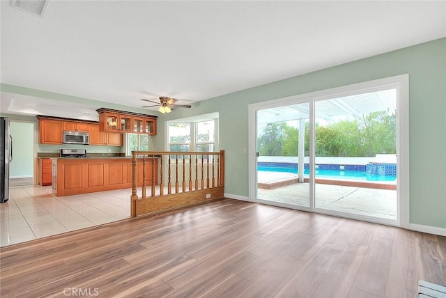 unfurnished living room with ceiling fan and light wood-type flooring