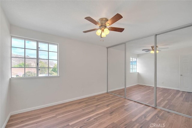 unfurnished bedroom with wood-type flooring, ceiling fan, and a closet