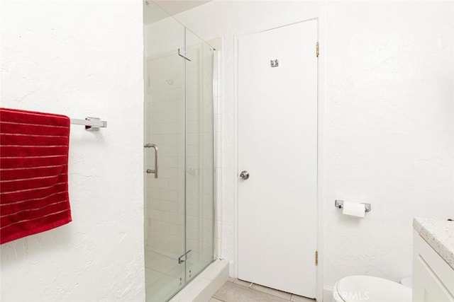 bathroom featuring vanity, toilet, a shower with shower door, and tile patterned flooring