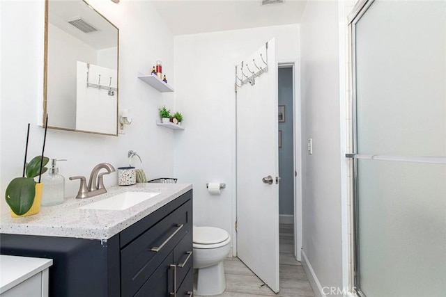 bathroom featuring vanity, toilet, a shower with shower door, and wood-type flooring