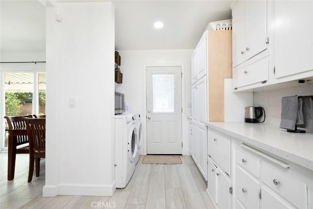 laundry room featuring cabinets, light wood-type flooring, and independent washer and dryer