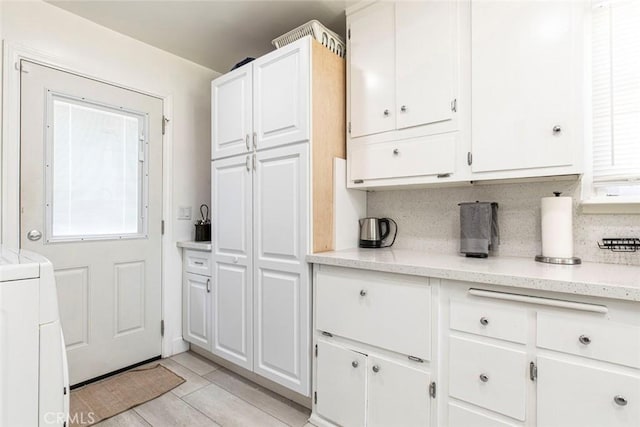 kitchen with white cabinetry, washer / clothes dryer, backsplash, and light tile patterned floors