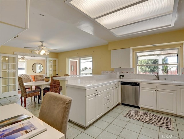 kitchen featuring light tile patterned flooring, white cabinetry, sink, stainless steel dishwasher, and kitchen peninsula