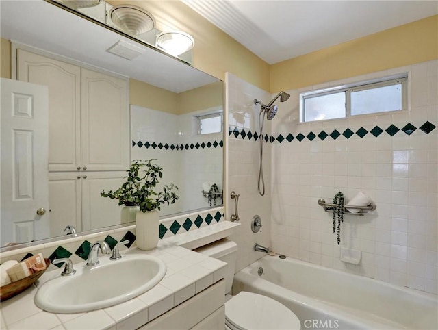 full bathroom with sink, tiled shower / bath combo, and toilet