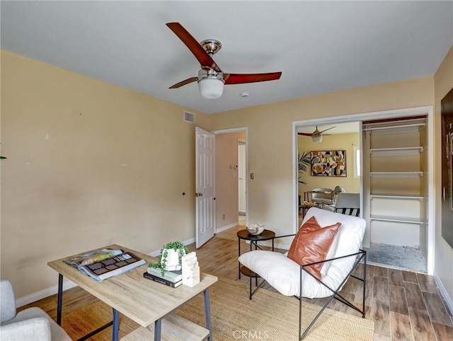 living area with hardwood / wood-style floors and ceiling fan