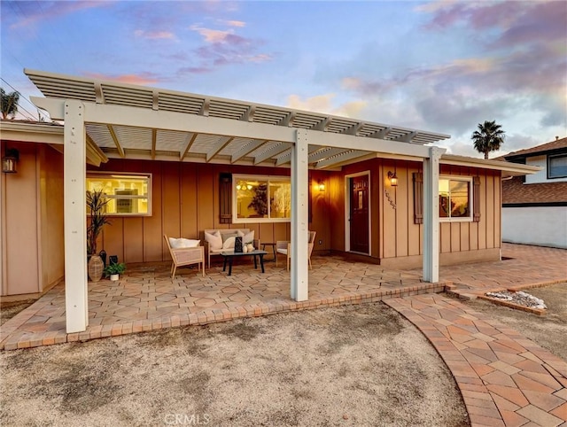 back house at dusk featuring an outdoor living space, a pergola, and a patio