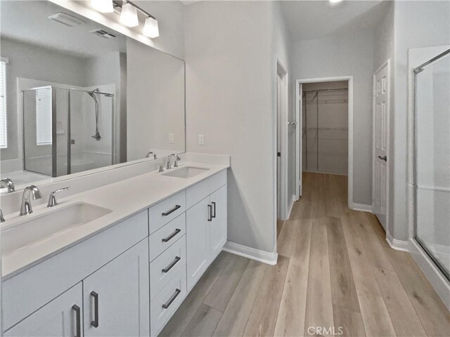 bathroom with a shower with door, vanity, and wood-type flooring