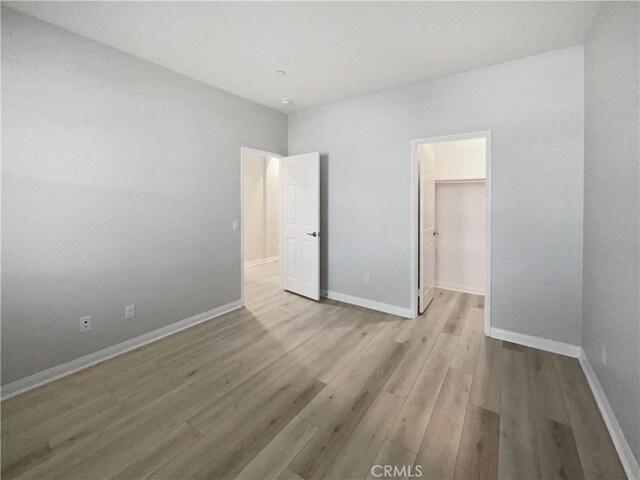 unfurnished bedroom with a walk in closet and light hardwood / wood-style flooring