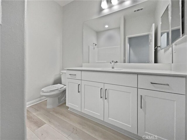 bathroom with vanity, hardwood / wood-style floors, walk in shower, and toilet