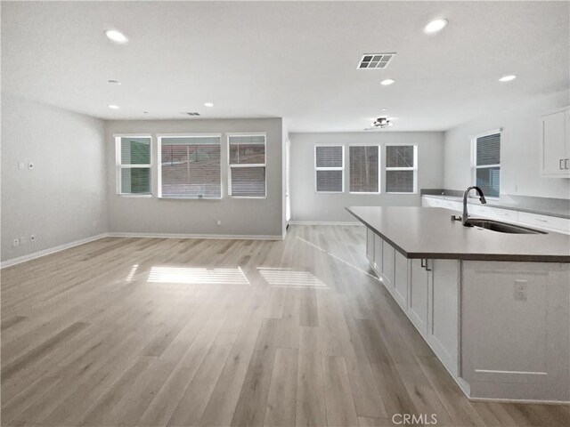 kitchen with white cabinetry, sink, light hardwood / wood-style floors, and a breakfast bar