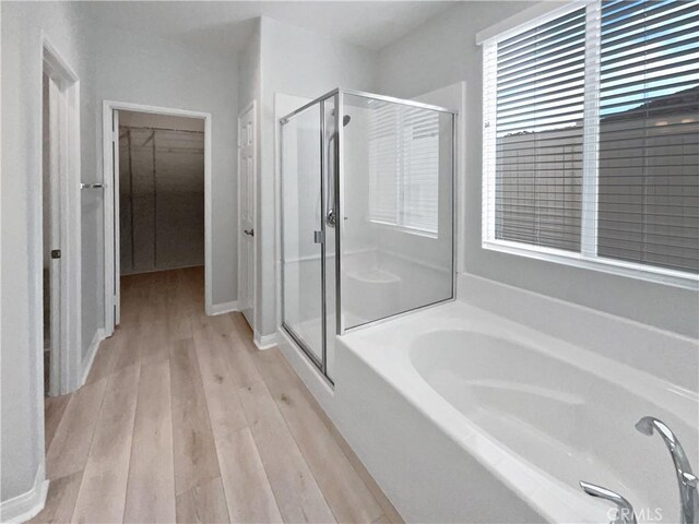 bathroom featuring plus walk in shower and hardwood / wood-style floors