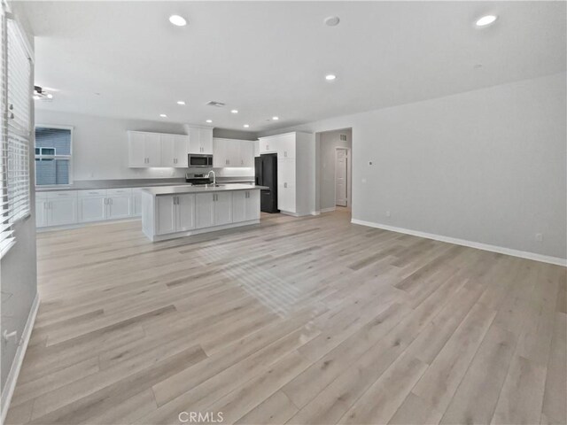 unfurnished living room featuring sink and light wood-type flooring