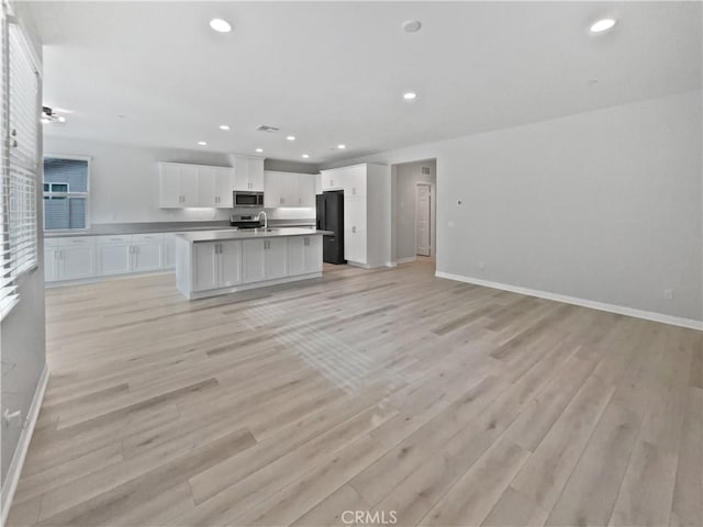 unfurnished living room with sink and light hardwood / wood-style flooring