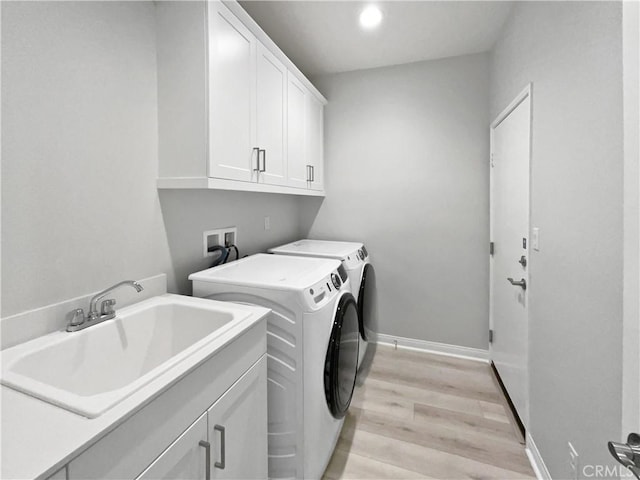 clothes washing area with sink, light hardwood / wood-style flooring, cabinets, and independent washer and dryer