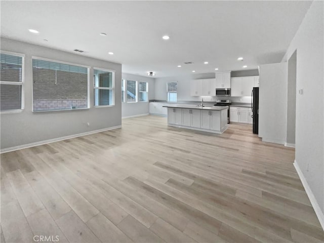 5393 Viewstone Ct, Hemet, CA 92545 - kitchen with stainless steel microwave, open floor plan, freestanding refrigerator, light wood-style flooring, and white cabinets