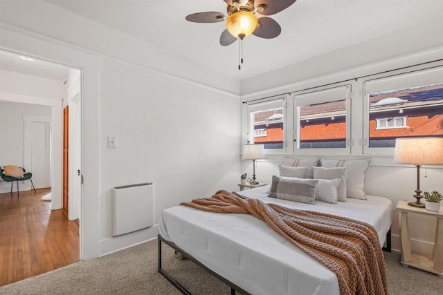 carpeted bedroom with heating unit and ceiling fan