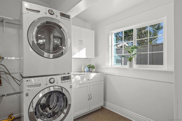 clothes washing area with cabinets and stacked washer / dryer