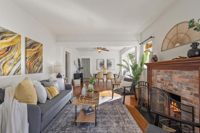 living room featuring dark wood-type flooring, ceiling fan, and a fireplace