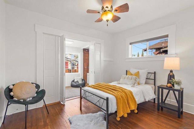 bedroom featuring multiple windows, dark wood-type flooring, and ceiling fan