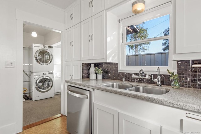 kitchen with white cabinetry, sink, stacked washer / drying machine, stainless steel dishwasher, and light stone counters