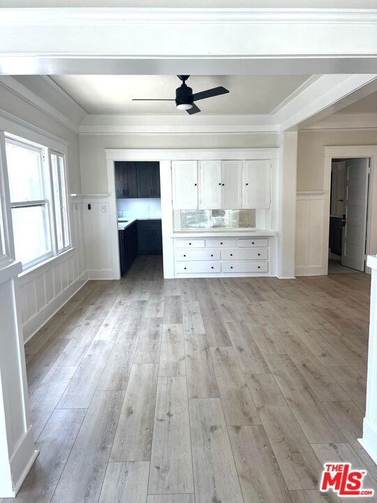 unfurnished living room featuring ceiling fan, ornamental molding, and light hardwood / wood-style floors