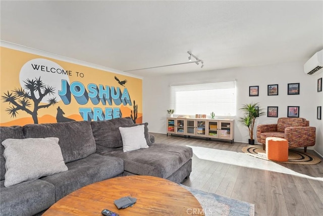 living room featuring wood-type flooring, ornamental molding, track lighting, and a wall unit AC