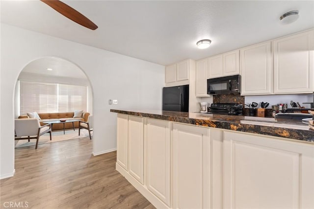 kitchen featuring white cabinetry, dark stone countertops, tasteful backsplash, black appliances, and light hardwood / wood-style floors