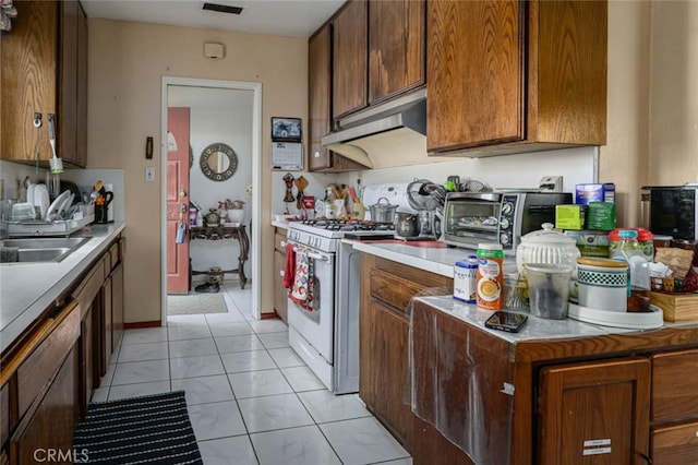 kitchen with sink, white range with gas stovetop, and light tile patterned floors