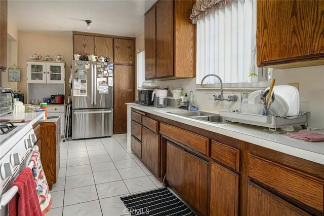 kitchen featuring stainless steel refrigerator, light tile patterned flooring, sink, and white range with gas stovetop