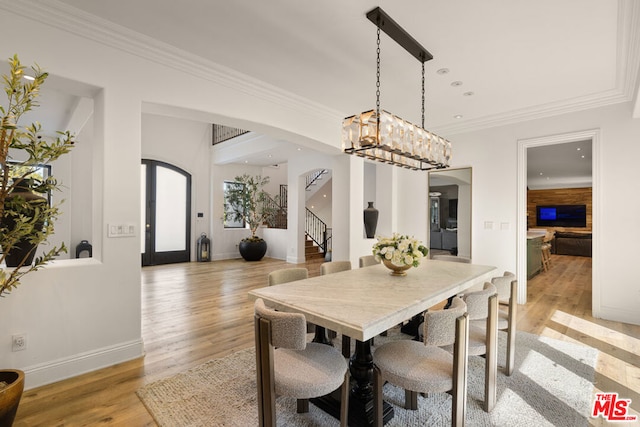 dining room featuring crown molding, light wood-type flooring, and french doors